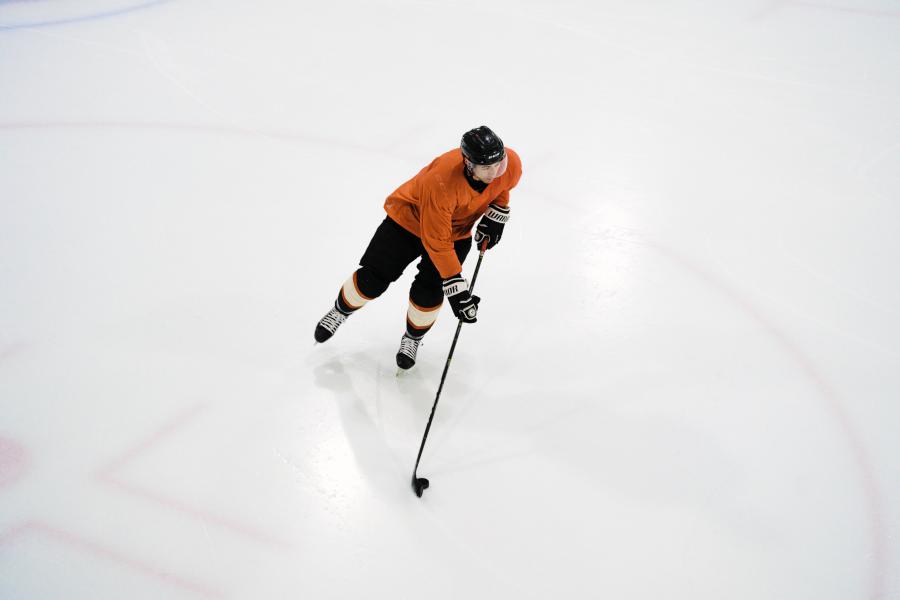 Aerial view of a hockey player skating on the ice, move the puck with his stick.