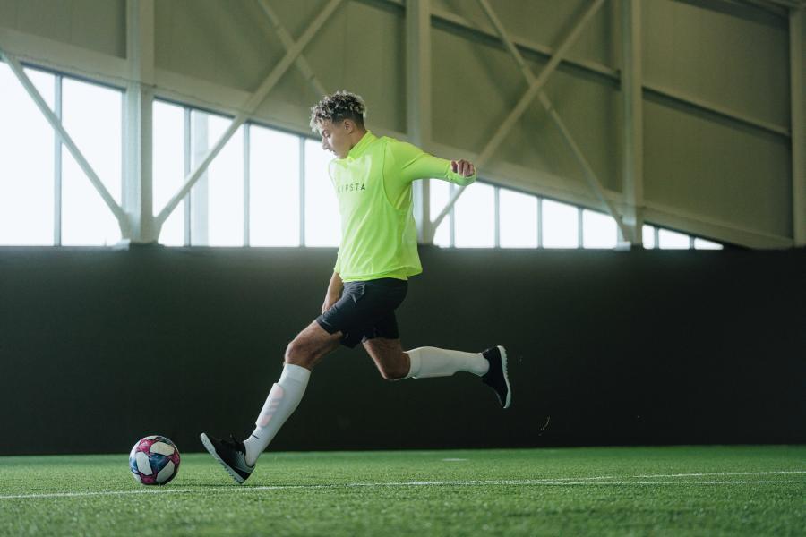 A soccer player is in motion to kick the ball.