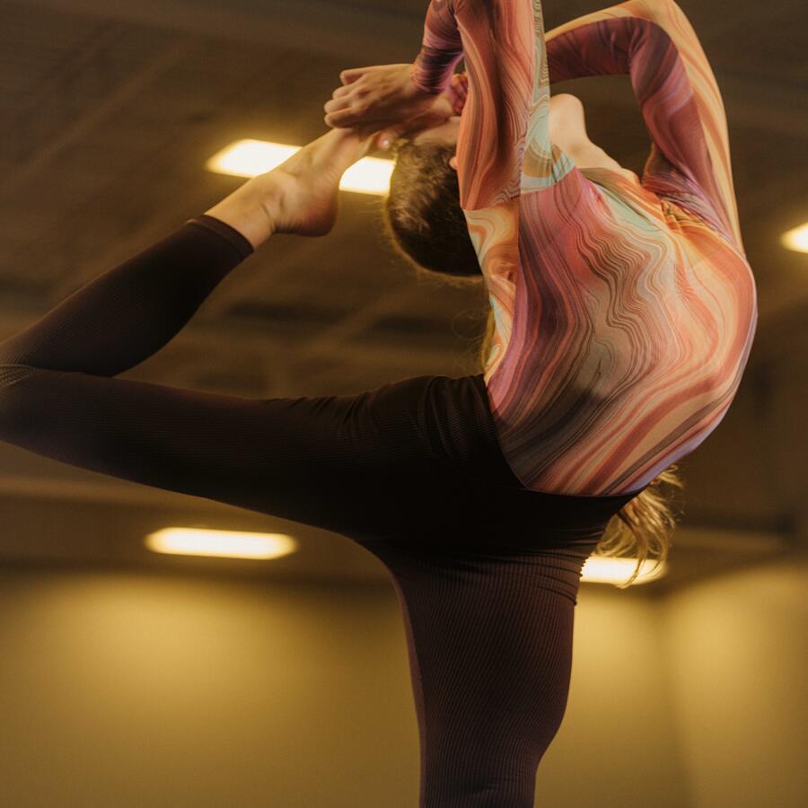 Gymnast standing up in leg behind head pose. 