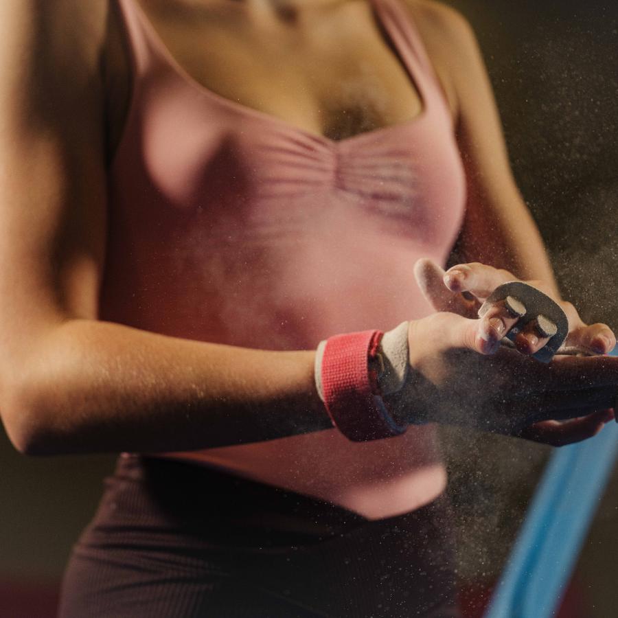 A gymnast putting white chalk on her hands.