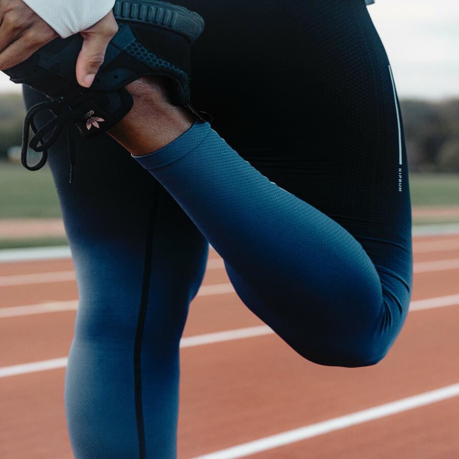 Closeup on a runner stretching her quads.