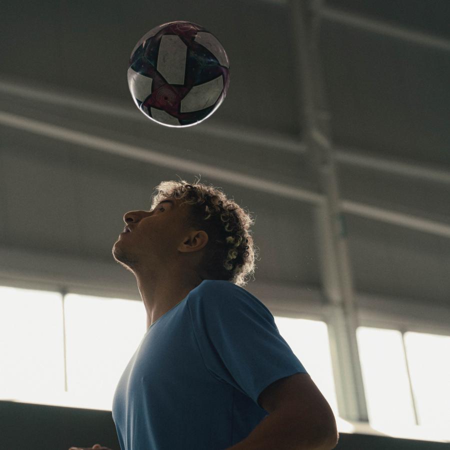 A soccer player practices heading the ball. 