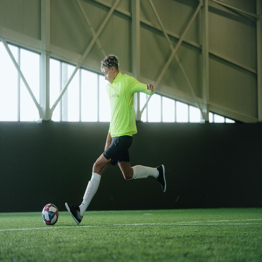 A soccer player is in motion to kick the ball.