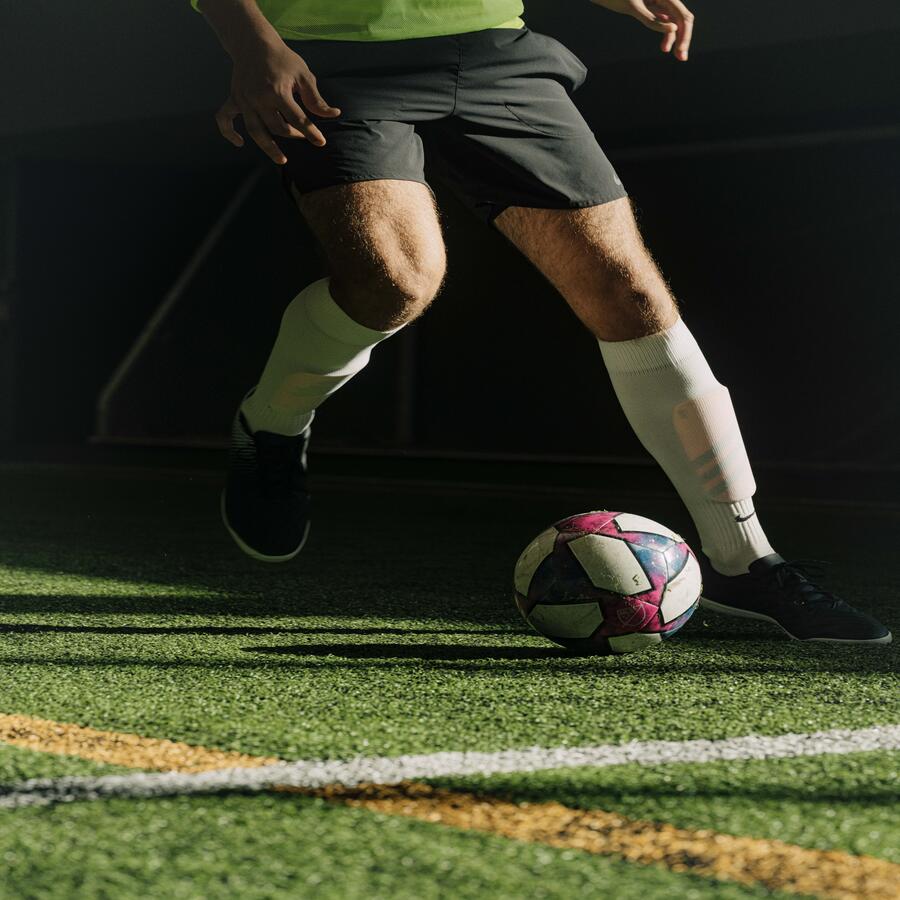 A soccer player Is running on the field with the ball.