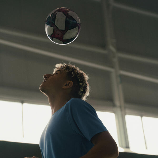 A soccer player practices heading the ball.